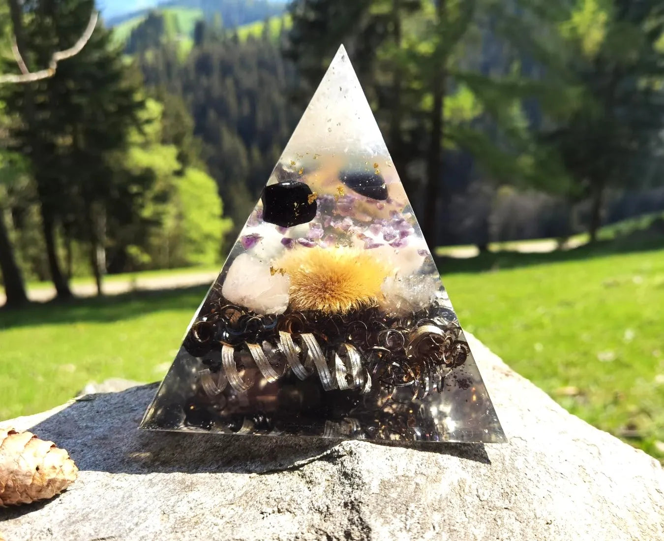 Detailansicht der Aura-Vita Orgon Energiepyramide mit Fokus auf die Heilsteine und die Goldistel im Inneren.