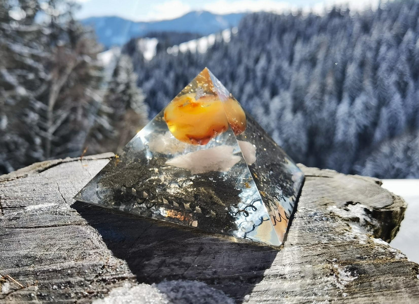 Seitenansicht der Karneol-Flammenpyramide, die mit leuchtendem Karneol und klaren Kristallen auf einem Baumstamm präsentiert wird.