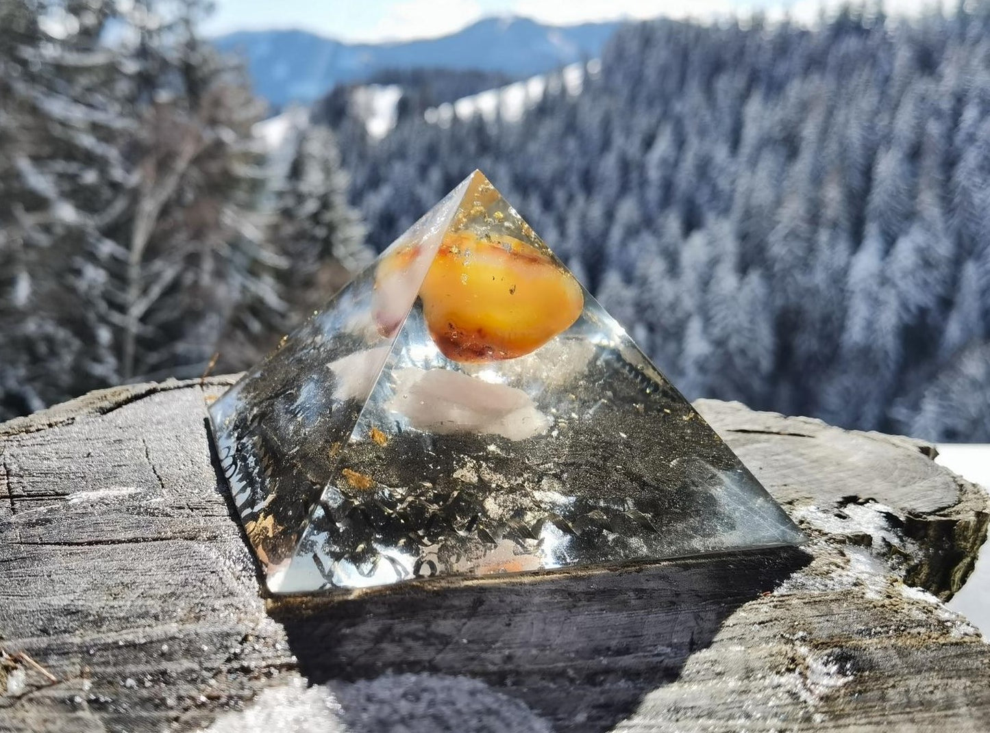 Vorderansicht der handgefertigten Karneol-Flammenpyramide mit Rosenquarz und Bergkristall vor einer verschneiten Berglandschaft.
