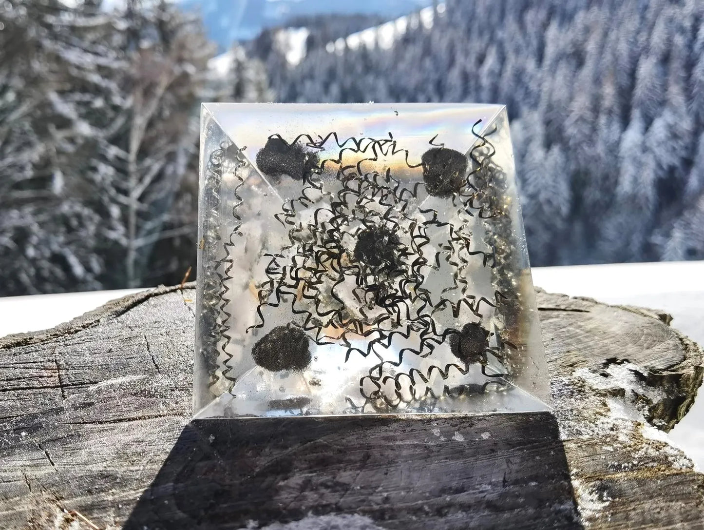 Handgefertigte Kristallfeuerwerk Orgon-Pyramide mit Opal & Bergkristall für spirituelle Entwicklung und positive Energiearbeit in einer friedvollen Landschaft.