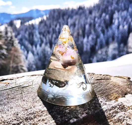 Orgonit Kegel mit Amethyst, aufgenommen vor einem klaren Himmel und schneebedeckten Bergen, symbolisiert spirituelle Klarheit und Energie.