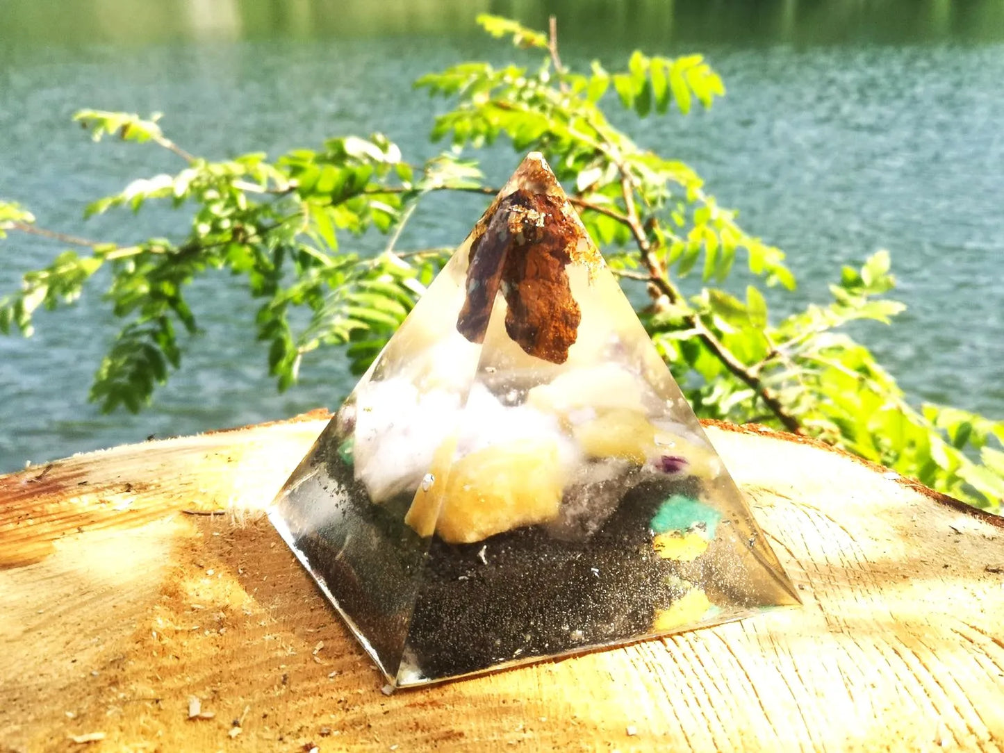 Seelenlicht Orgonit-Pyramide mit Opal, Calcit & Amazonit in einer natürlichen Umgebung am See, ideal für Harmonie und Schutz.