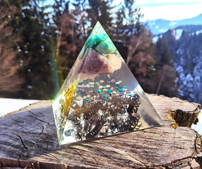 Handgefertigte Lebenskraft-Pyramide aus Kristallen auf einem Holzstamm.