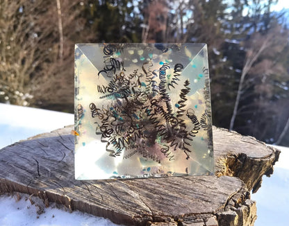 Energiepyramide mit Amazonit und Amethyst vor einer Berglandschaft.