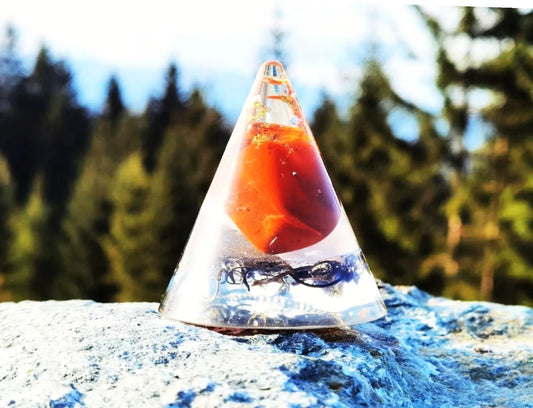 Orgonit-Kegel mit rotem Jaspis, Rosenquarz und Bergkristall, ideal für das Wurzelchakra und spirituelle Harmonie, fotografiert in der Natur.